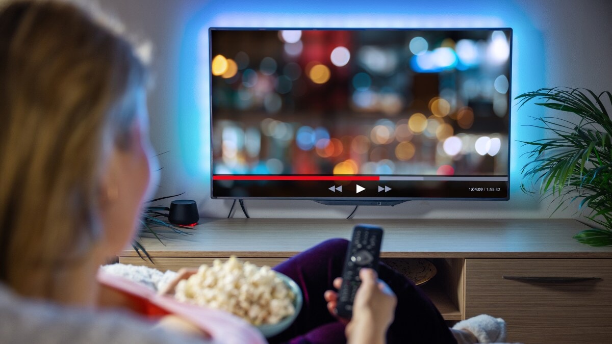 Femme se détendant à la maison le soir et regardant la télévision